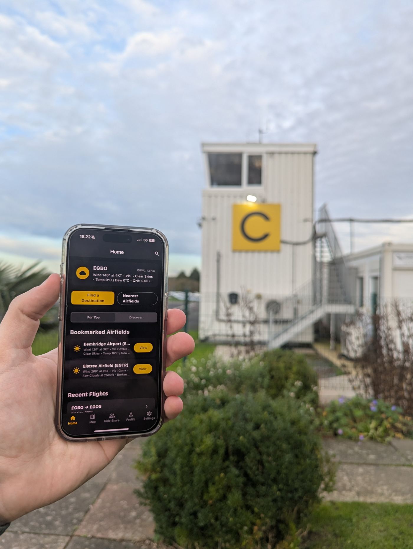 A pilot holding the Landaways app open at an airfield control tower